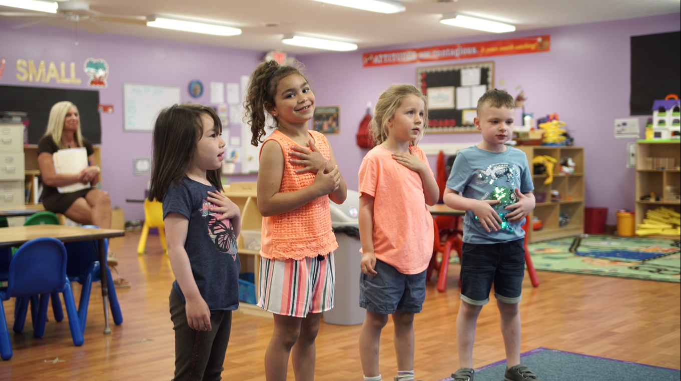 Four children standing for the pledge of allegiance | Pleasant Day Schools